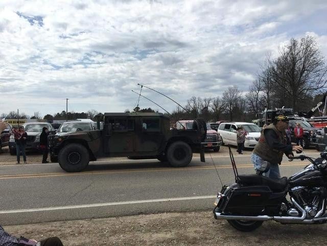 A dark colored mi humvee is parked on the side of a road